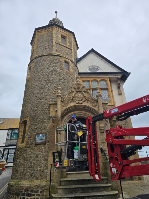 Man standing on work equipment in front of the Guildhall building in Lyme Regis