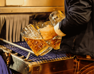 An image of someone holding 4 large Oktoberfest Stein glasses filled with beer