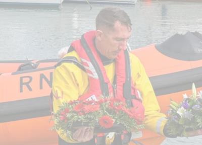 Lyme Regis RNLI crew member with flower wreaths at blessing of the boats ceremony