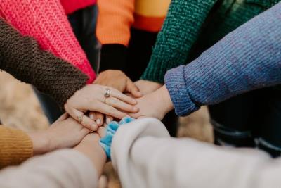 people joining hands, wearing knitted jumpers