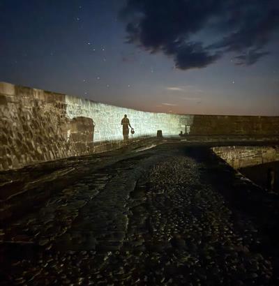 Lifeboat crew member silhouetted against the Cobb wall