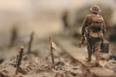 a sepia image of a lone soldier walking on a dusty front line