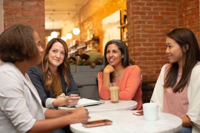 An image of 4 ladies sitting around a table happily chatting