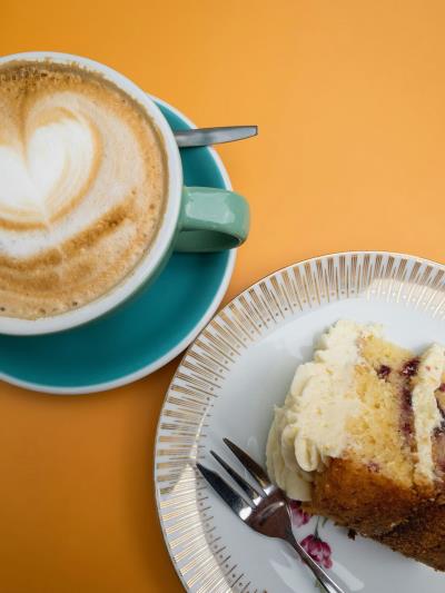 Coffee mug and saucer with piece of jam sponge cake as a flatlay