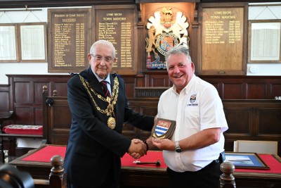mayor Cllr Philip Evans presenting a commemorative town shield to volunteer Lifeboat Operations Manager Mark Colley.
