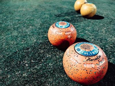 3 lawn bowls in a row on a bowling green in the sunshine
