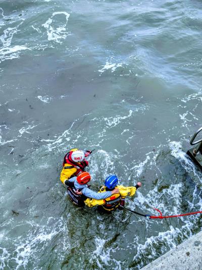 Image of Coastguard rescuing casualties, wading in a metre of water back to safety