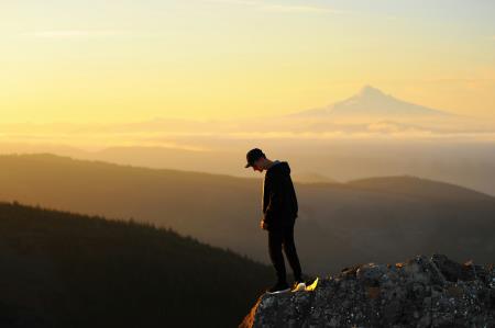 a photo of a teenager against a setting sunset in the mountains 