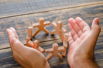 a photo of a pair of hands holding wooden symbols of community abstract
