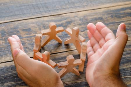a photo of a pair of hands holding wooden symbols of community abstract