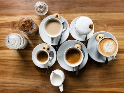 an aerial photo of mugs of coffee and tea on a wooden table taken from above 