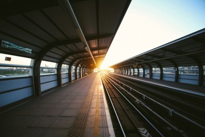 an image of an empty train track at a train station at sunrise